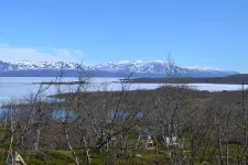 Landskap med sjö och snöklädda berg. Foto