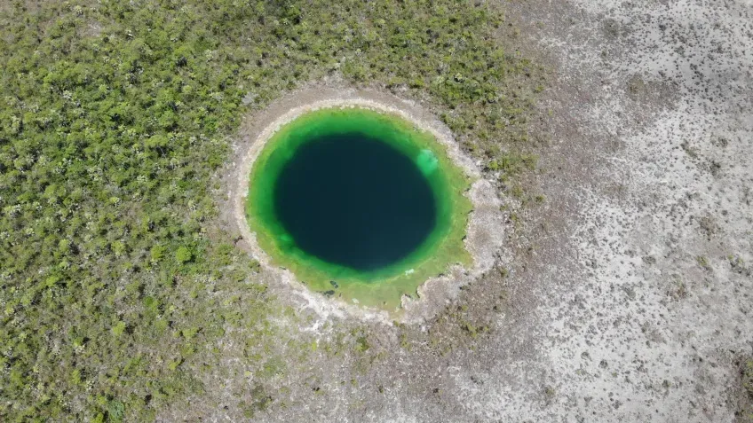 Flygfoto av ett runt svart vattenfyllt hål.